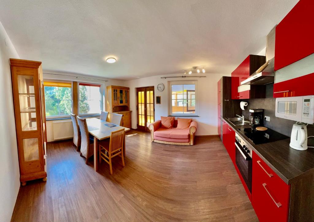 a kitchen and living room with red cabinets and a table at Apartment Florence in Wettringen
