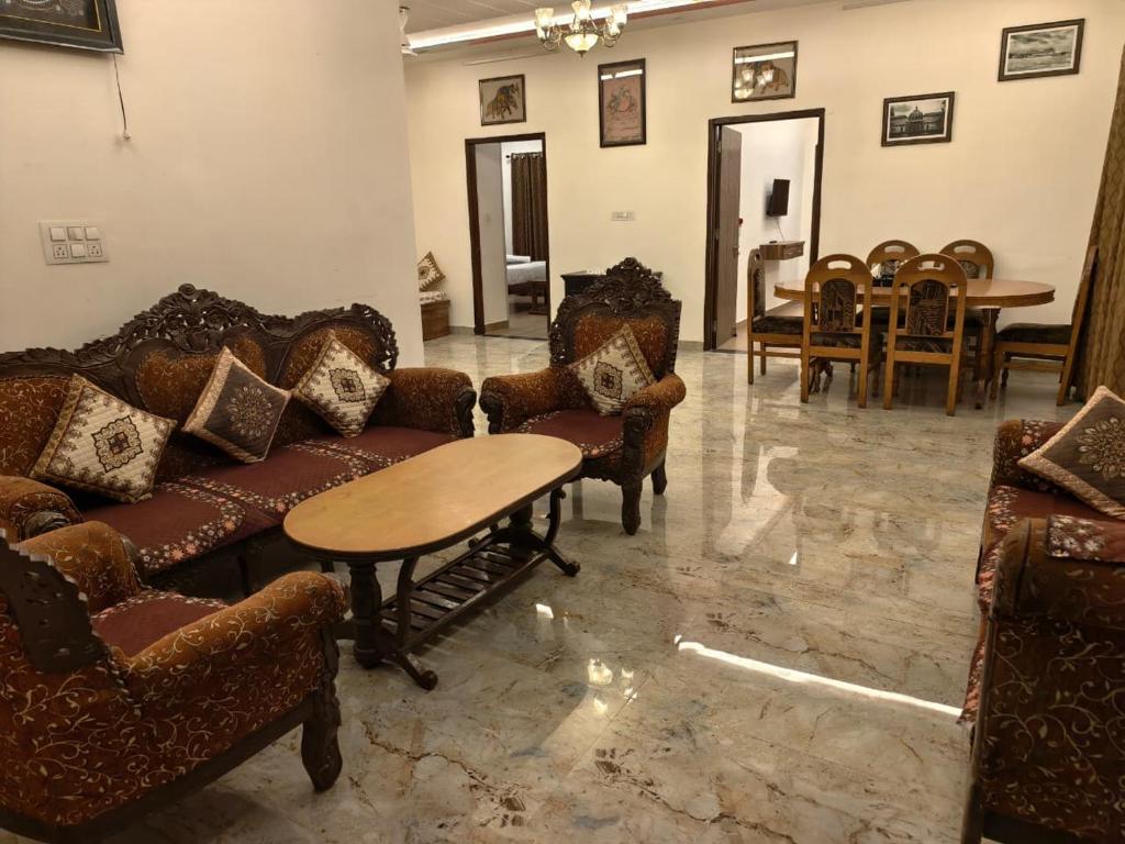 a living room with couches and a table and chairs at Rayta Aravalli View Villa in Udaipur