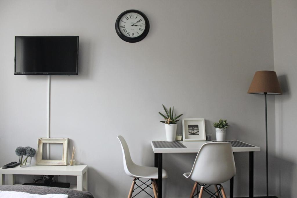 Pokój z biurkiem i zegarem na ścianie w obiekcie Noctis Apartment Nowogrodzka w Warszawie