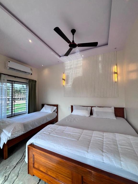 two beds in a bedroom with a ceiling fan at Hampi Tribes Homestay in Hampi
