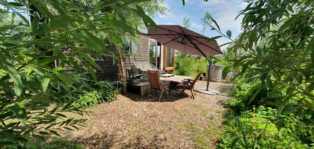a table and chairs under an umbrella in a yard at Tiny House Lau at Glamping Verbaarum in Bedum