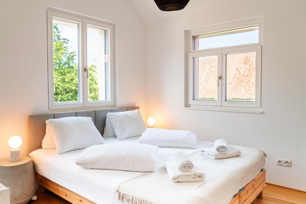 a bedroom with a large white bed with two windows at VINCENT Loft in der Innenstadt - mit Garage in Bregenz