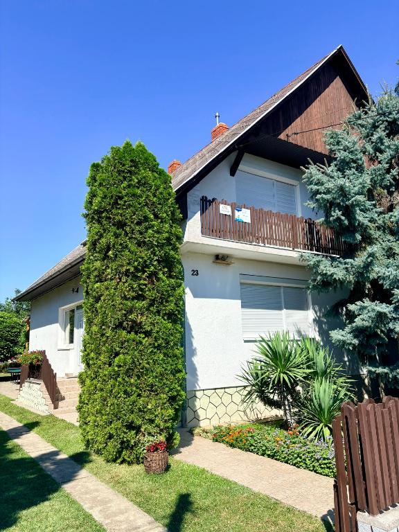 a white house with a hedge in front of it at Oli vendégház in Balatonboglár