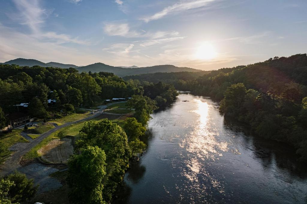 an aerial view of a river with the sun setting at Asheville River Cabins, WorldHotels Backdrop in Arden