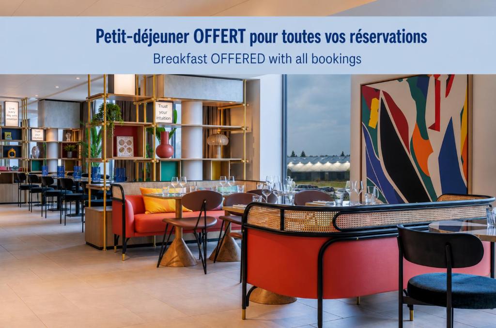 a restaurant with tables and chairs in a room at Hampton By Hilton Lyon Airport in Saint-Exupéry