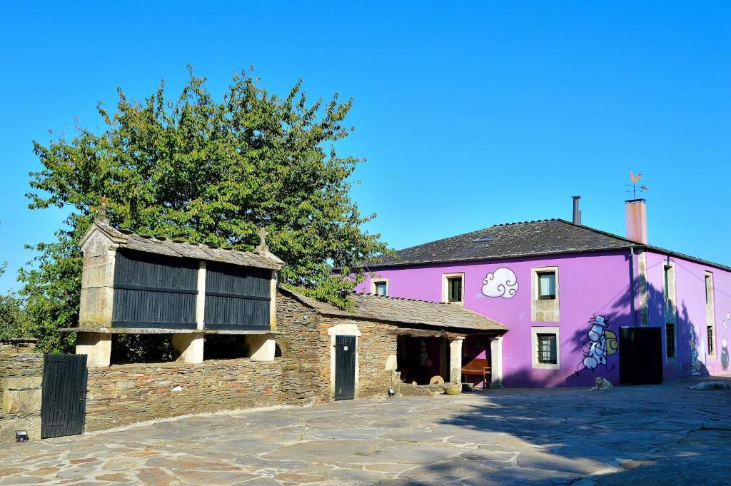 ein rosafarbenes Gebäude mit einem Baum davor in der Unterkunft Casa de Baixo in Lugo