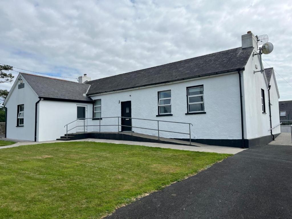 a white building with a grass yard in front of it at Clohanbeg School House in Kilrush