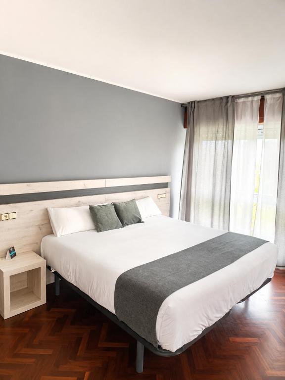a bedroom with a large white bed and a window at Alda Puerta Coruña in A Coruña