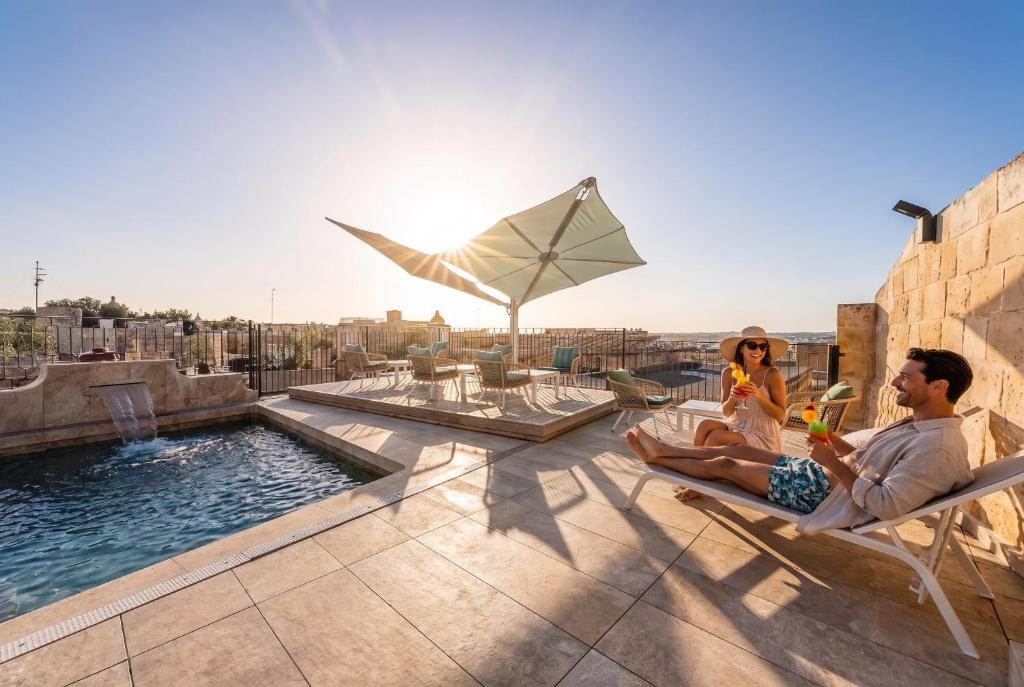 a man and a woman sitting in chairs on a roof at Palazzo Bifora Mdina in Mdina