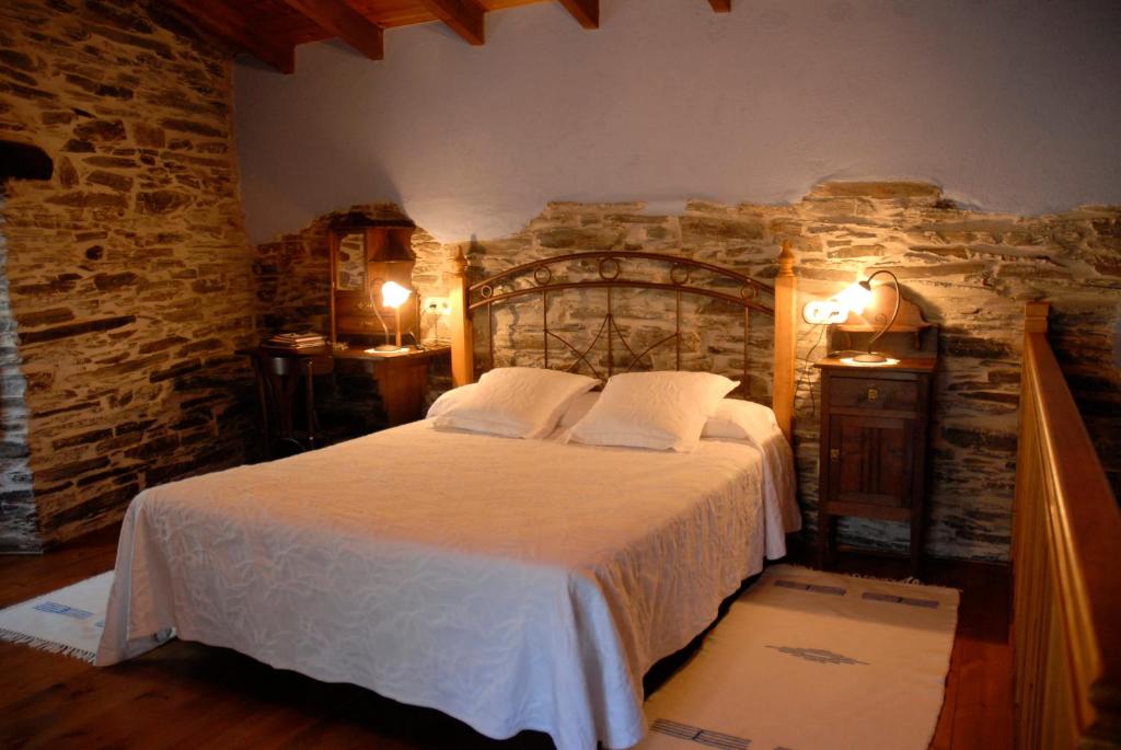 um quarto com uma cama grande e uma parede de pedra em Casa Grande da Ferreria de Rugando em Rugando