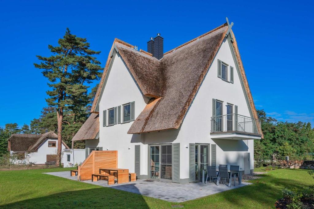 a large white house with a thatched roof at Fischerdorf DDH Hafftraum in Zirchow