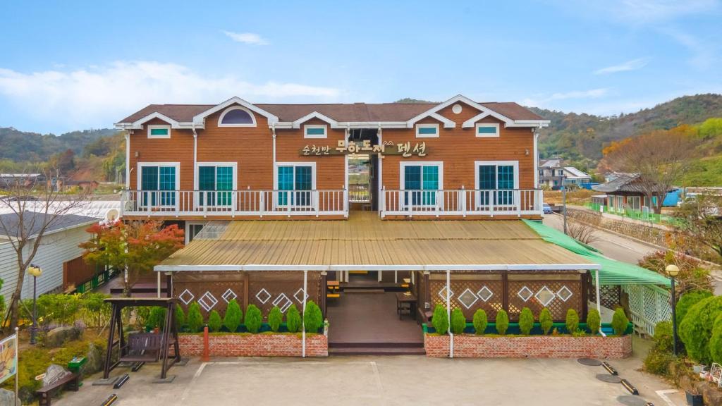 a large brown house with a large deck at Suncheonman Muhan Dojan Pension in Suncheon