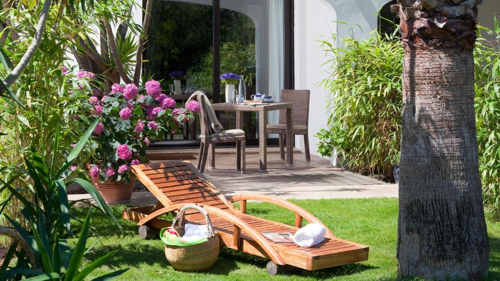 a garden with a bench and a table with flowers at Mangio Fango Hotel et Spa in Saintes-Maries-de-la-Mer