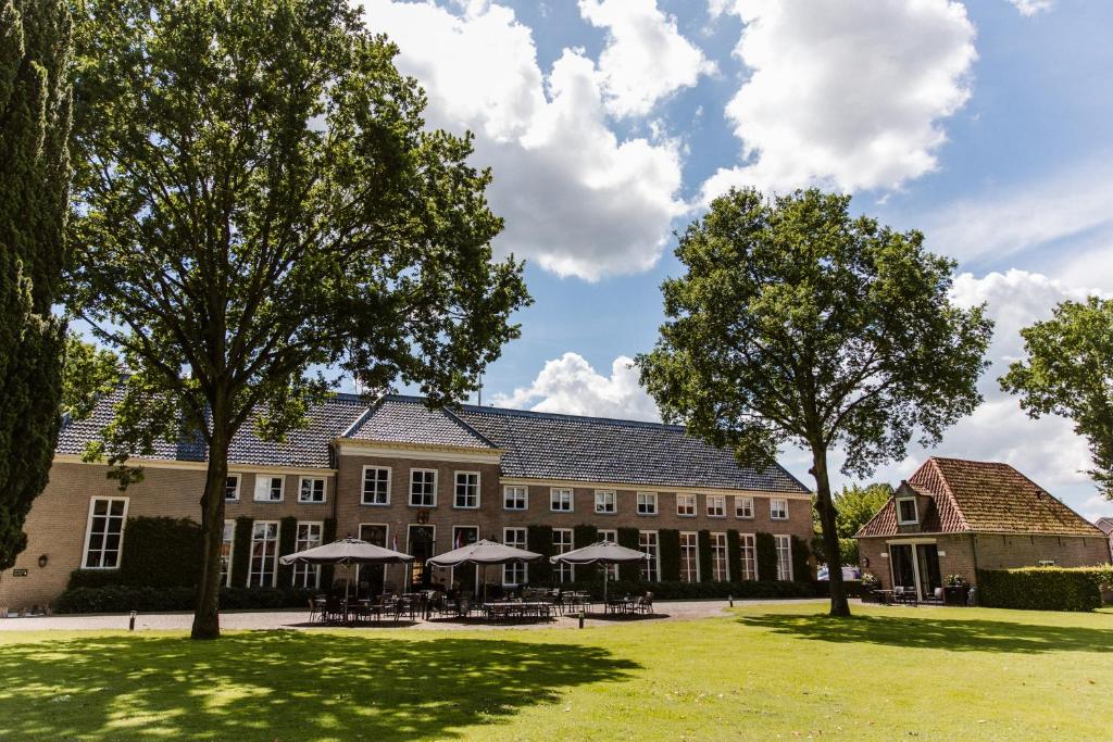 a large building with tables and umbrellas on a lawn at Stadspaleis Hotel & Restaurant OldRuitenborgh in Vollenhove