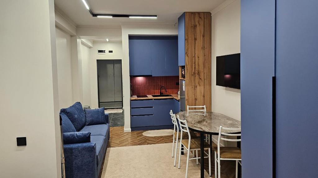 a living room and kitchen with a blue couch and a table at Квартира in Cholpon-Ata