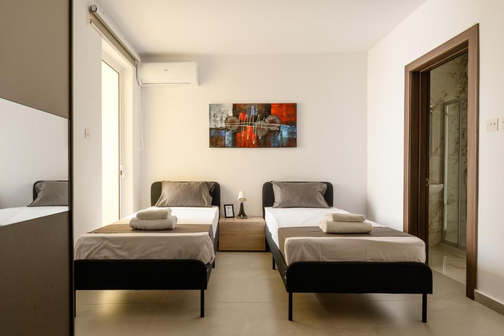 two beds in a room with white walls at F41 Private room ensuite shared flat in Il-Gżira