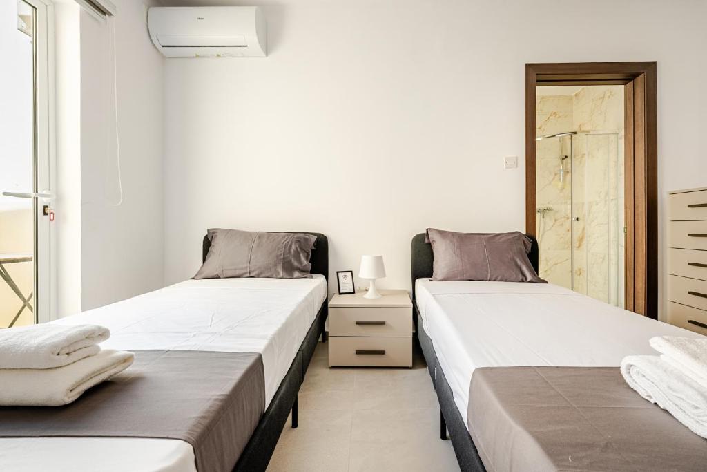 two beds sitting next to each other in a bedroom at GZR F51 Bedroom in Penthouse in Il-Gżira