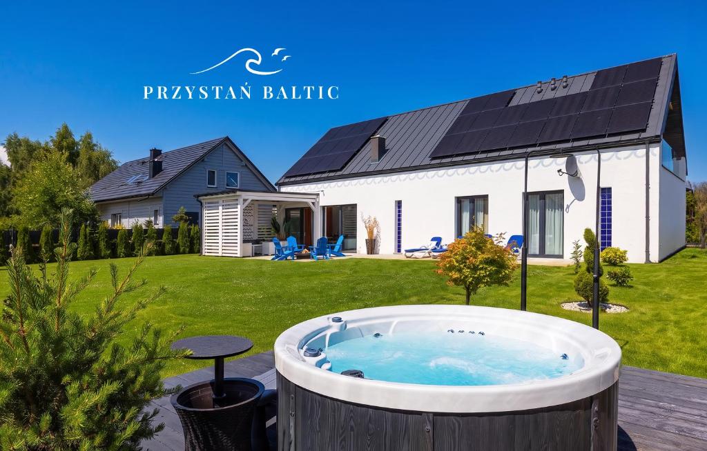 a hot tub in a yard in front of a house at Przystań Baltic - Holiday Luxury House Sauna & Jacuzzi in Zastań