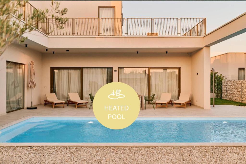 a hotel pool with a sign in front of a house at Taria Resort in Poreč