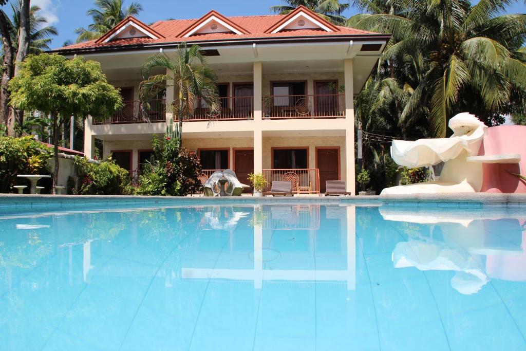 a large swimming pool in front of a house at Wellbeach Dive Resort in Zamboanguita