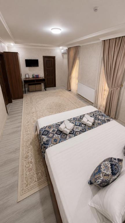 a hotel room with two beds and a desk at Abuzar in Bukhara