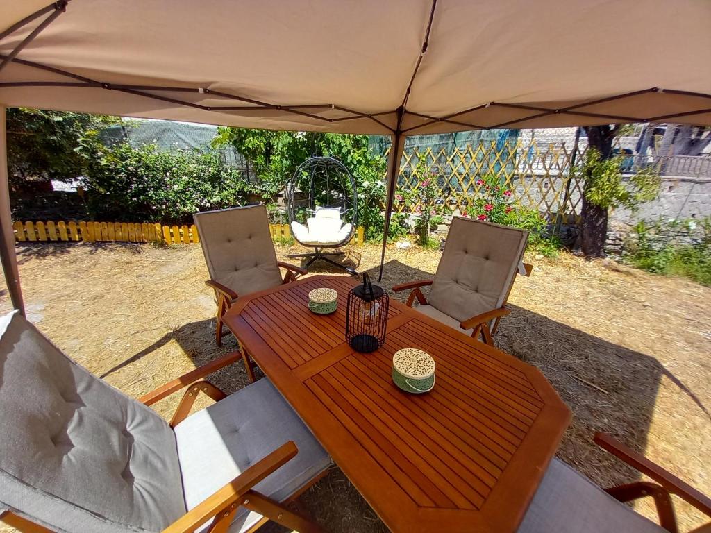 a wooden table and chairs under an umbrella at Belvedere di Van D'oro 1886 in Peroulades