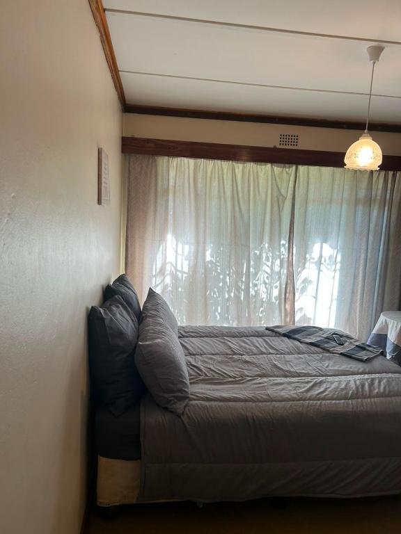 a bed sitting in a room with a window at Halkett Corner in Kimberley