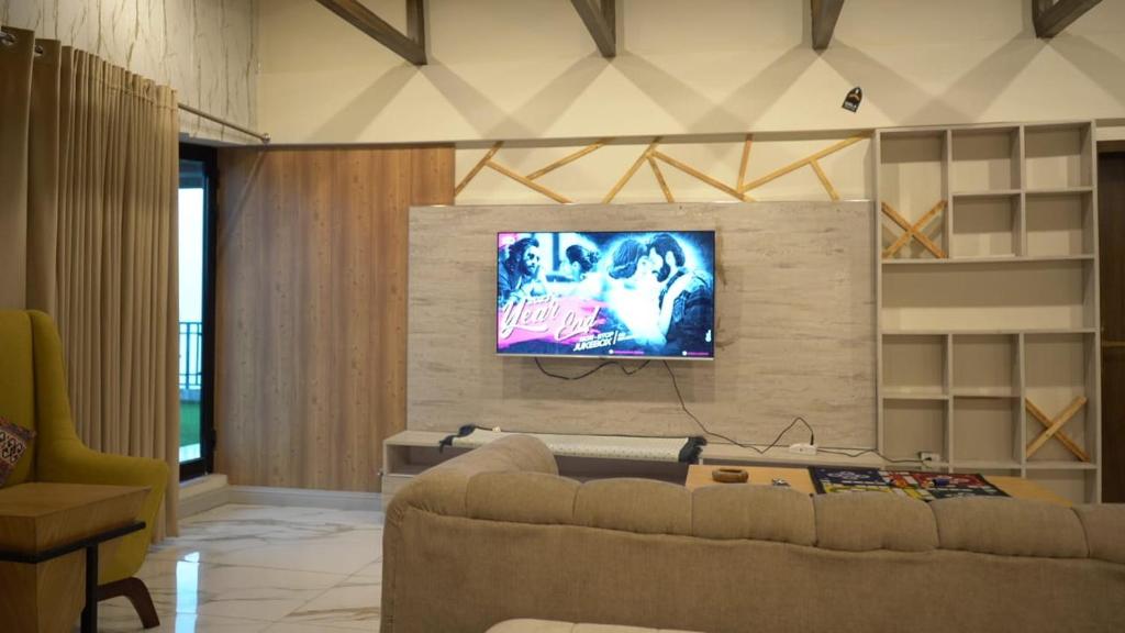 a living room with a couch and a tv on a wall at The Bliss avenue in Murree