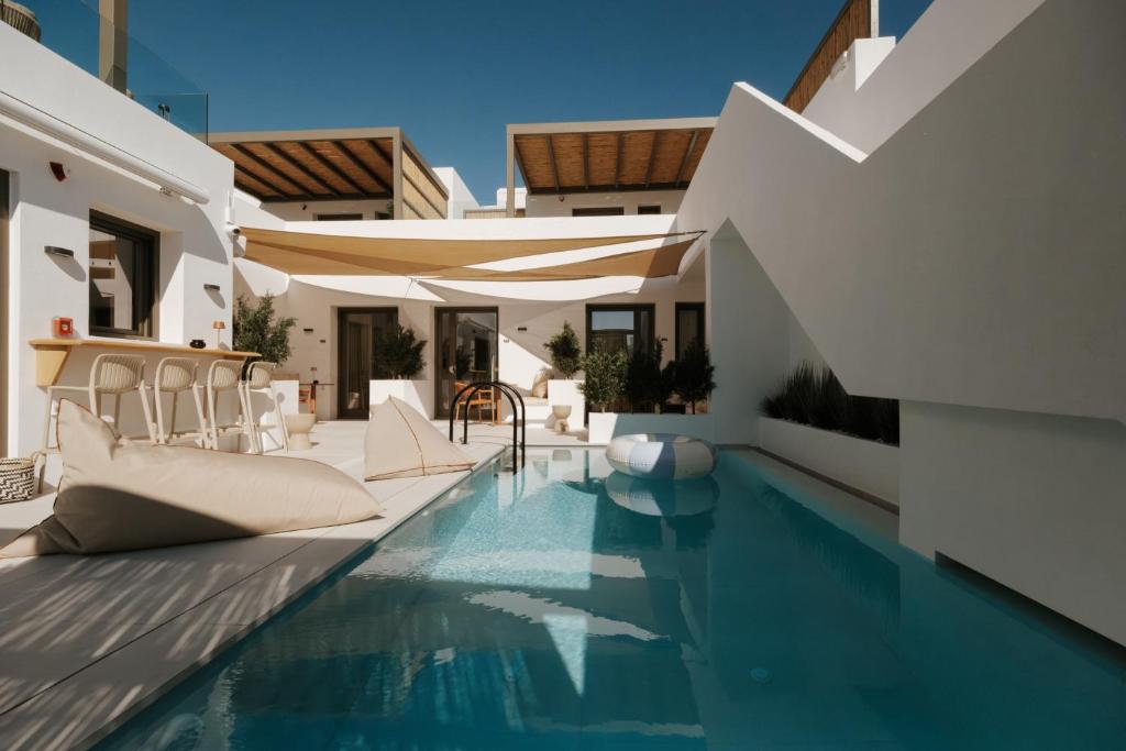 an infinity pool with chairs and tables in a house at The Lofts Paros Executive Suites in Naousa