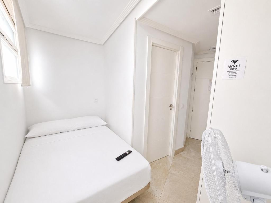 a white room with a bed and a mirror at Hospedaje La Campana in Madrid