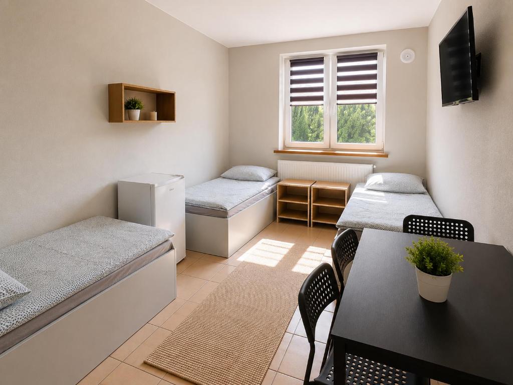 a small room with two beds and a table at Kwatery pracownicze in Łódź