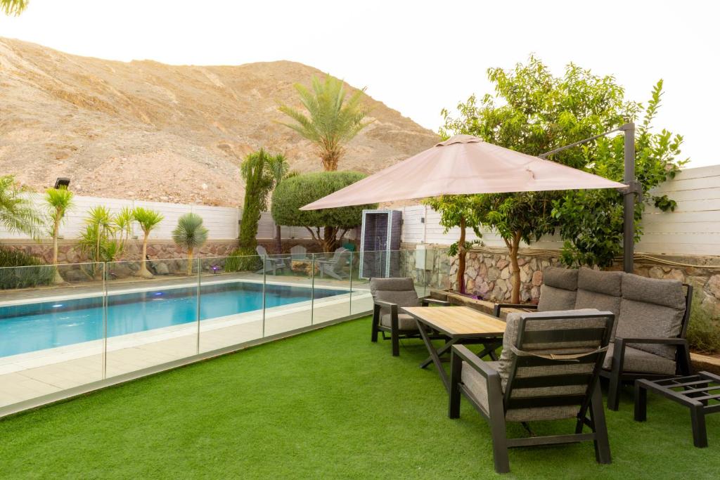 a patio with a table and chairs and a pool at שאנל דירת גן עם בריכה in Eilat