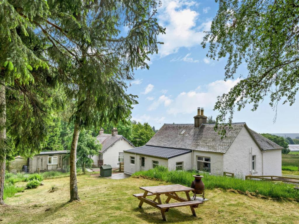 a picnic table in front of a white house at Upper Hillside Cottage in Blairgowrie