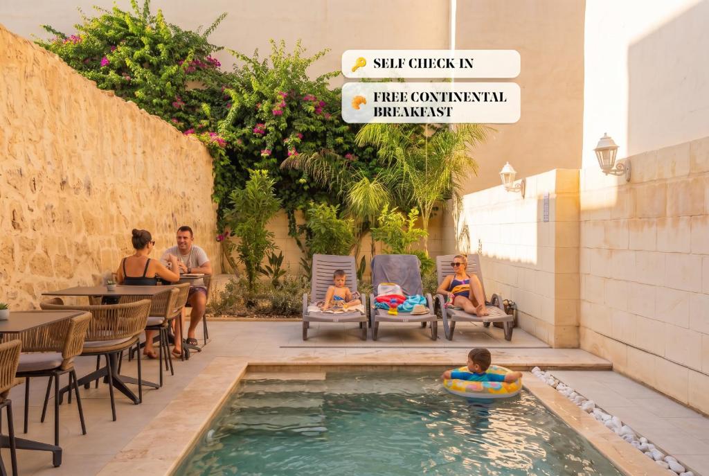 a group of people sitting around a pool at a restaurant at Mosta Stays by Zzzing in Mosta