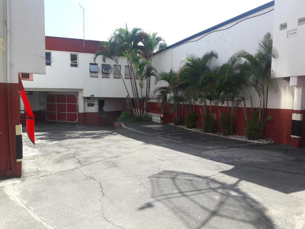 a parking lot in front of a building with palm trees at Motel Sedução in São Paulo