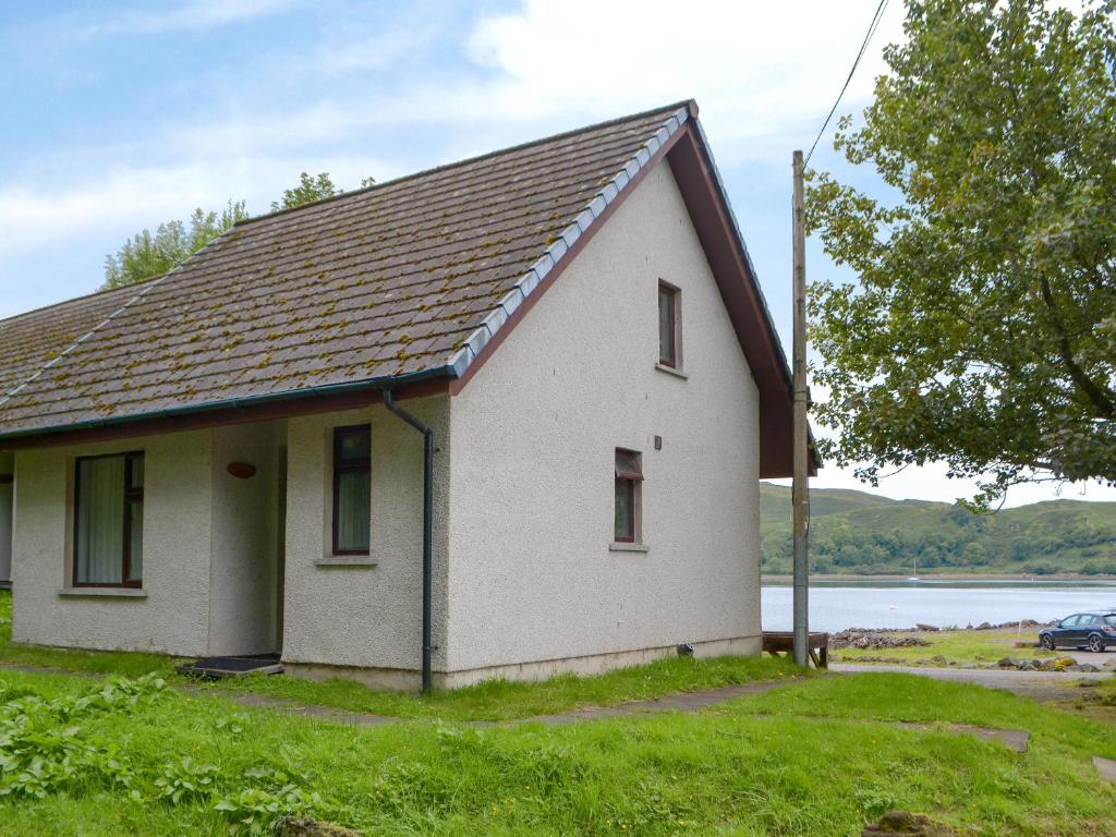 a small white house with a roof on the grass at Puffin - Bach in Lerags