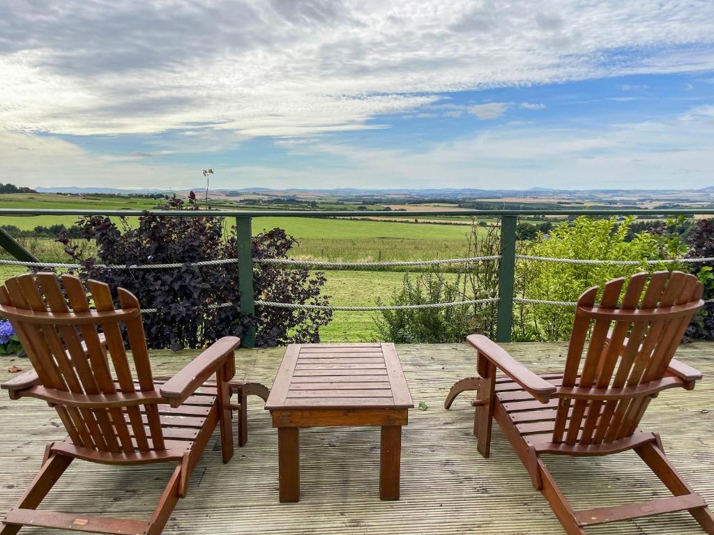 two chairs and a table on a deck with a view at Orange Yurt - Uk48018 in Gamrie