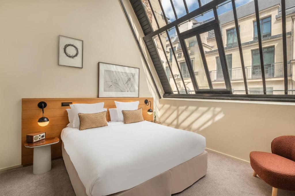 a bedroom with a large white bed and a large window at Maison Honnel in Paris