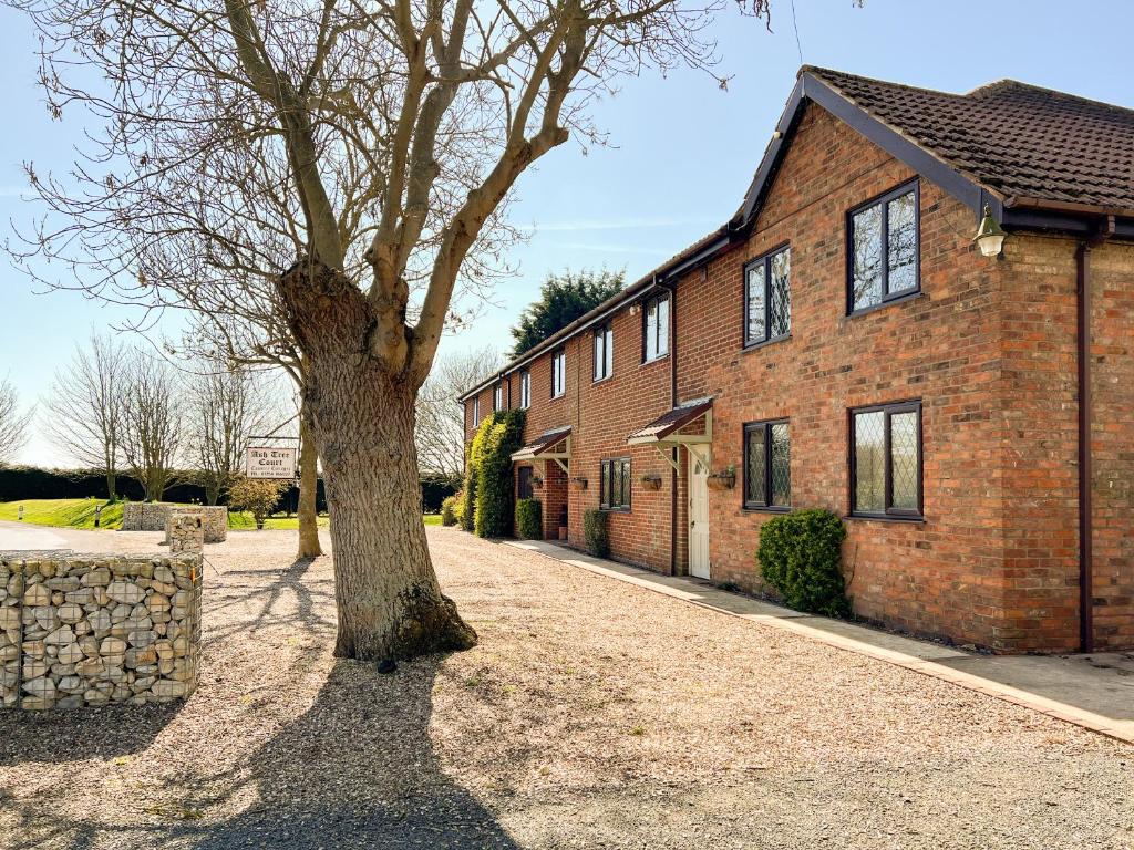 a tree in front of a brick building at The Old Barn-E1425 in Addlethorpe