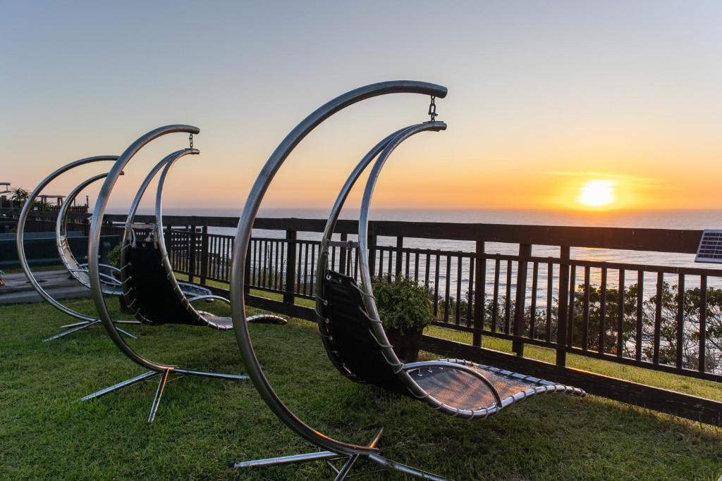 a group of chairs sitting on the grass near the beach at 305 Hotel in Amanzimtoti