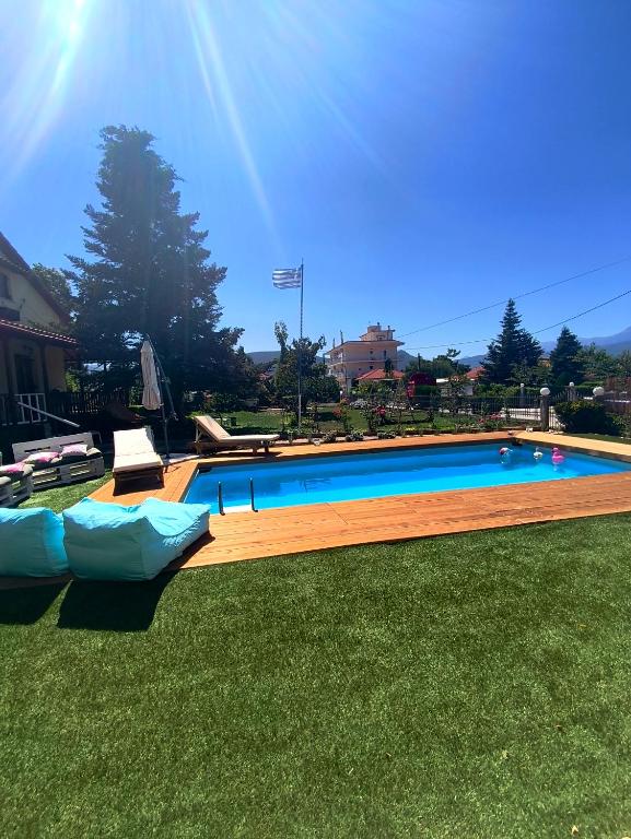 a large swimming pool in the grass with two chairs at Pool house Axiothea in Neméa