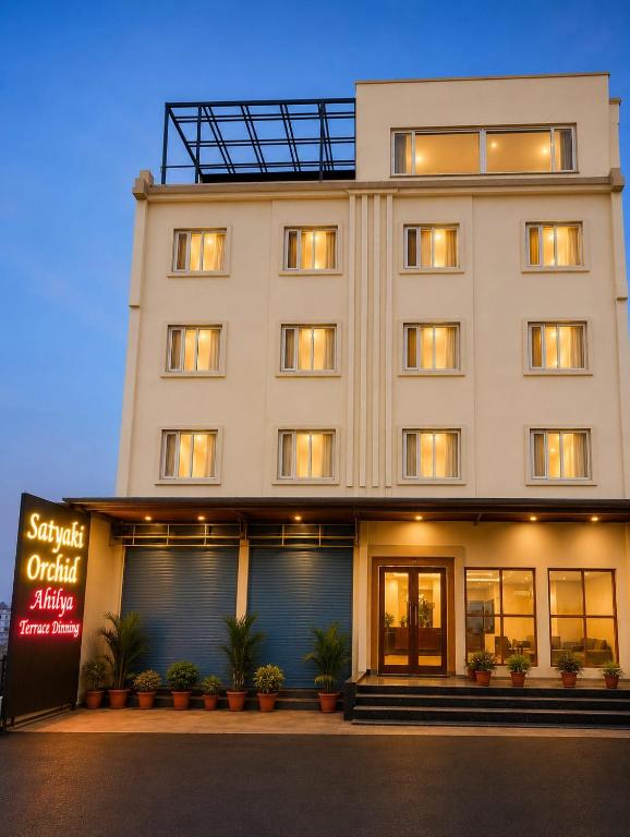 a large white building with plants in front of it at Hotel Satyaki Orchid in Katra