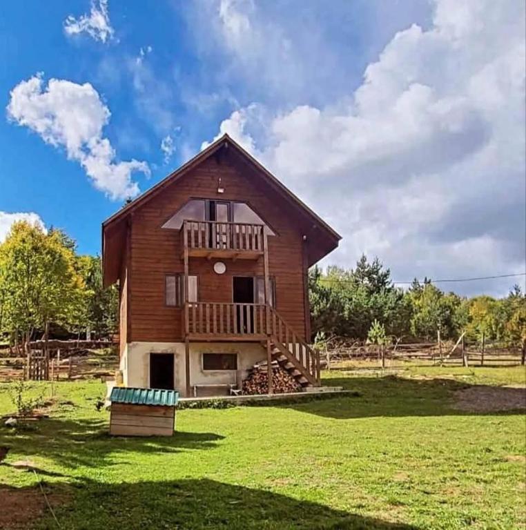 a large wooden house with a balcony on a green field at კერა მთაში Kera Mtashi in Ambrolauri