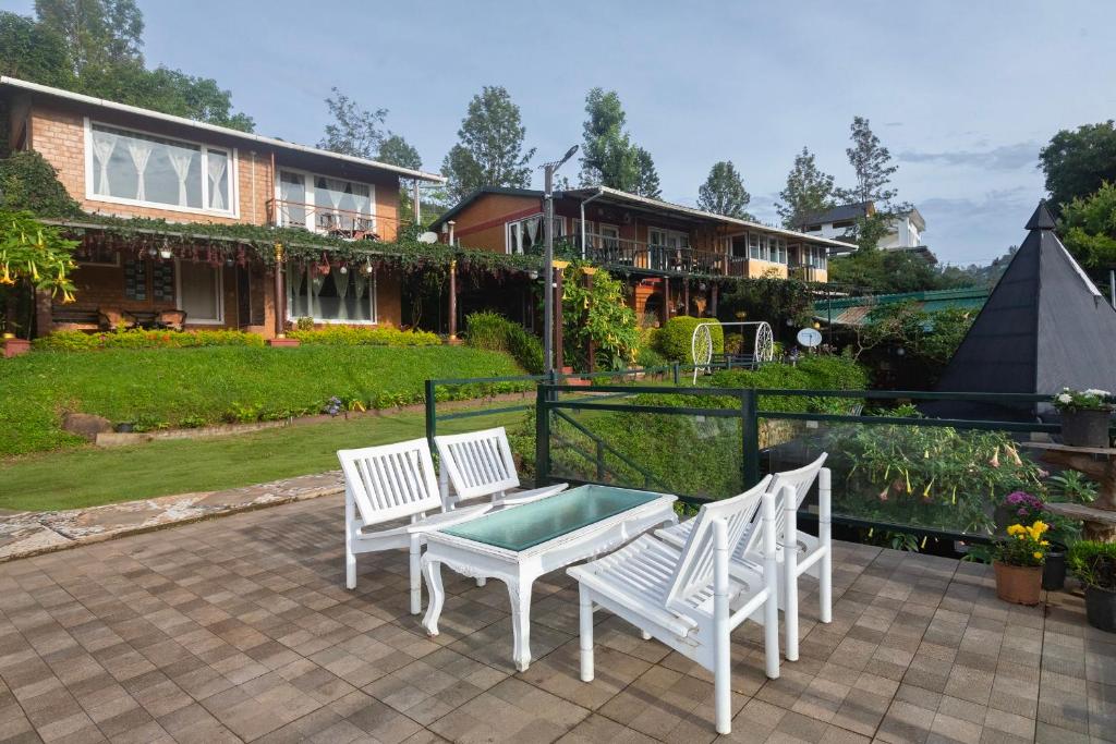 a patio with two white chairs and a table at De Rock Jungle Living Resort in Coonoor