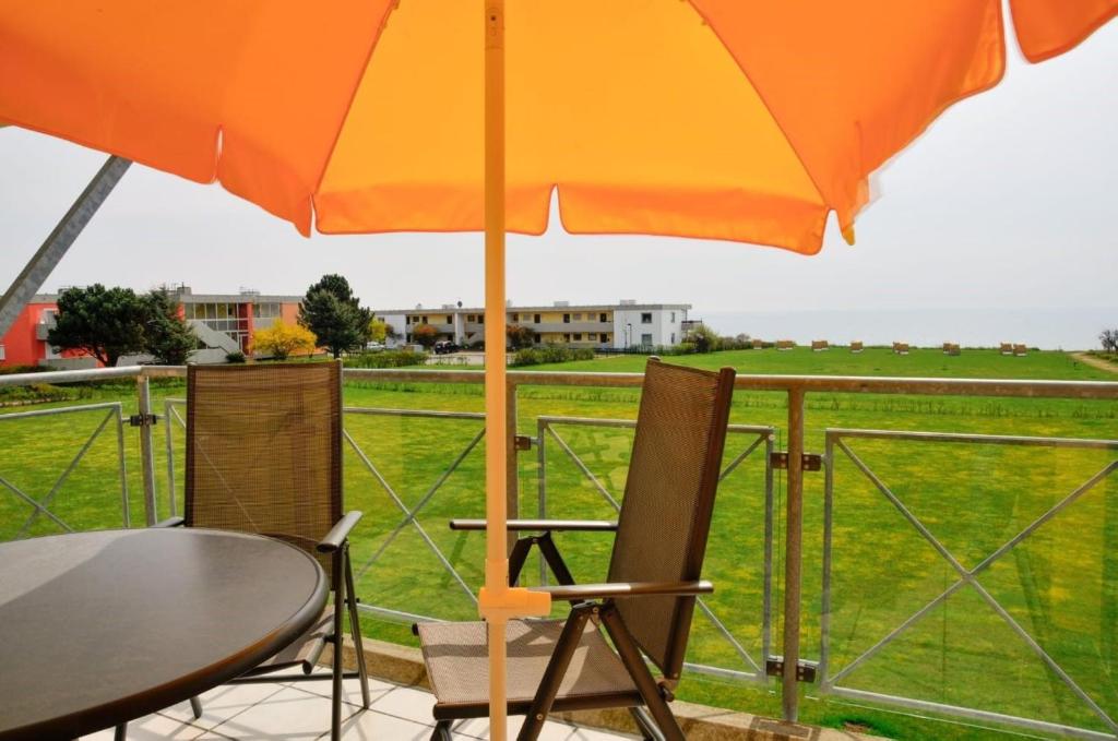 a table and chairs with an umbrella and a field at Meeresrauschen in Fehmarn