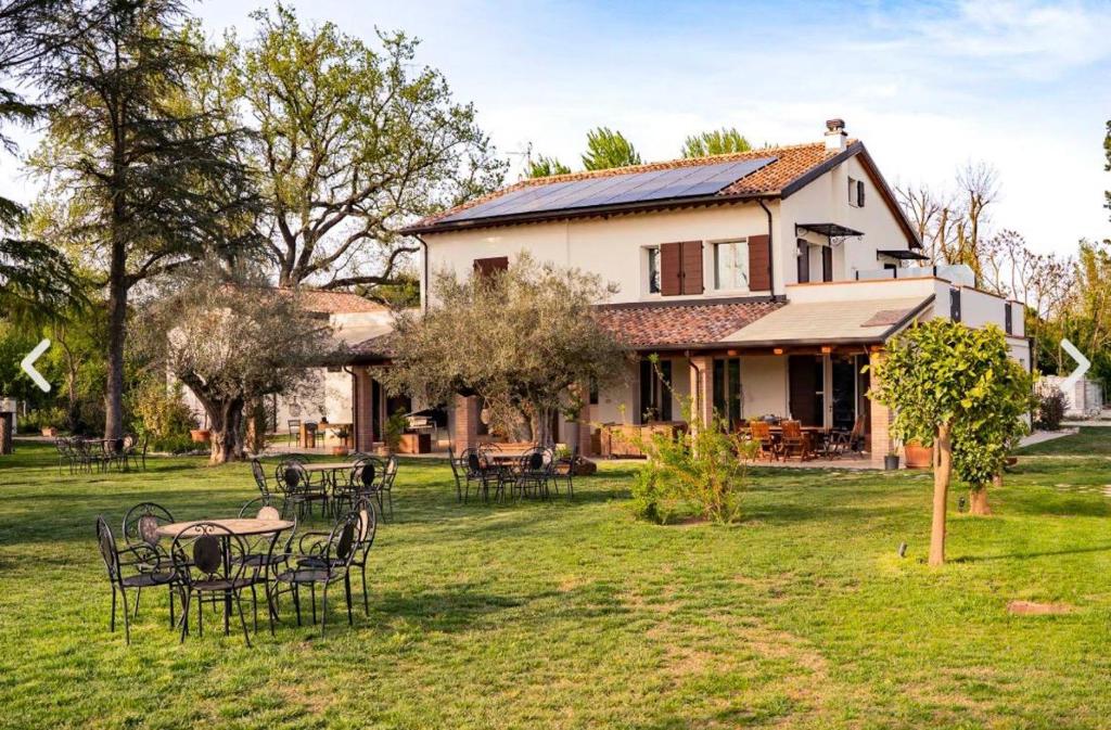 a house with tables and chairs in the yard at Podere Luna Stella in Bellaria-Igea Marina