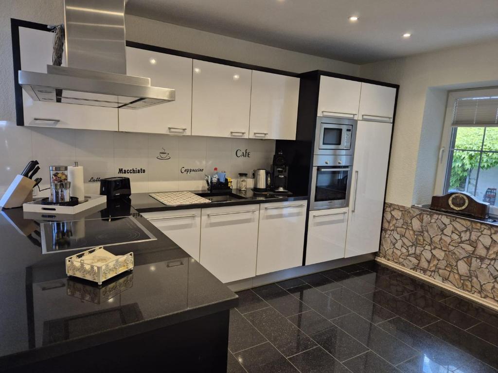 una cucina con mobili bianchi e un frigorifero di House Eifelglück a Großlittgen