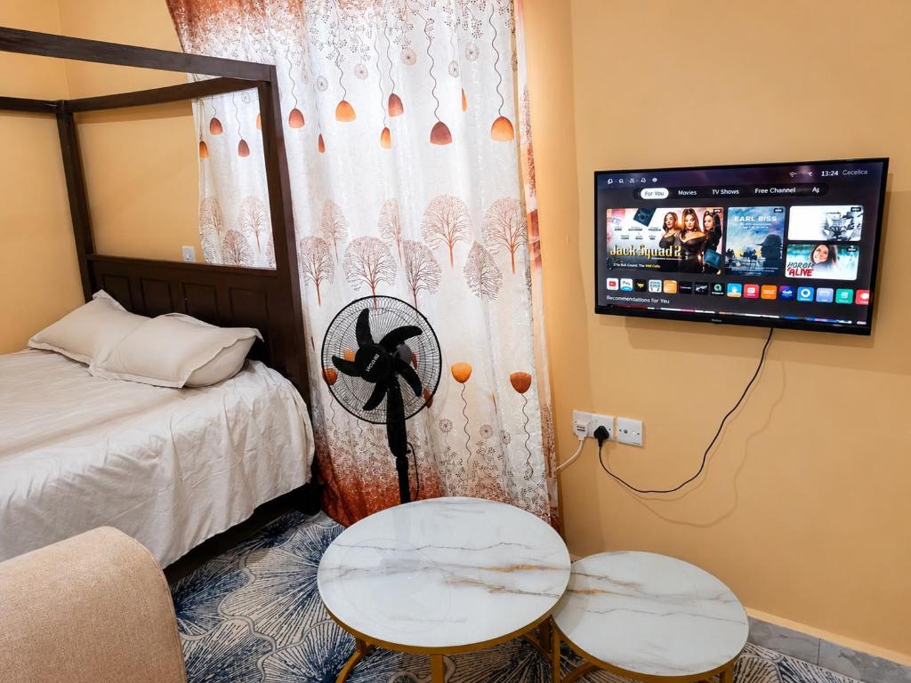 a room with a bed and two tables and a tv at Maria VillaSTUDIO2 in Voi