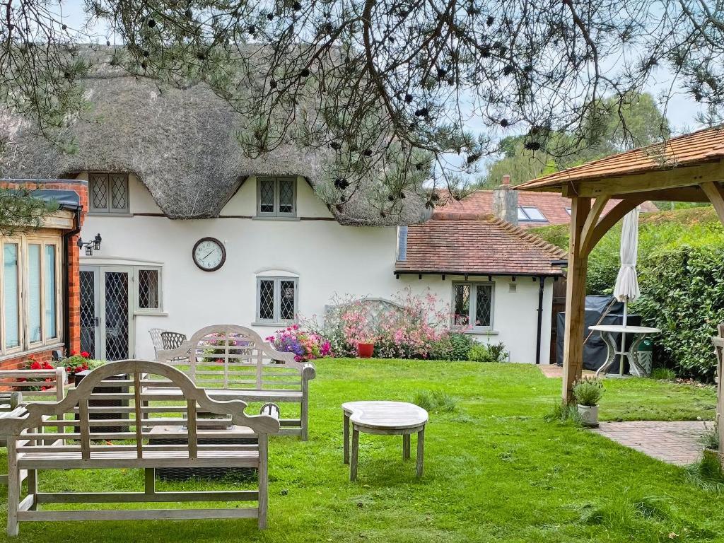 a house with two benches and a table in the yard at Pond Cottage in Alton