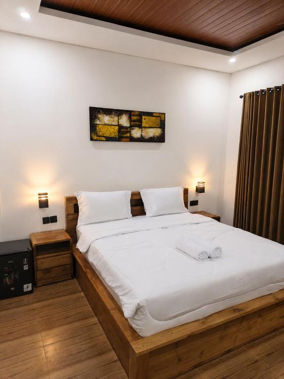 a bedroom with a large bed with white sheets at Luling Guesthouse in Badung
